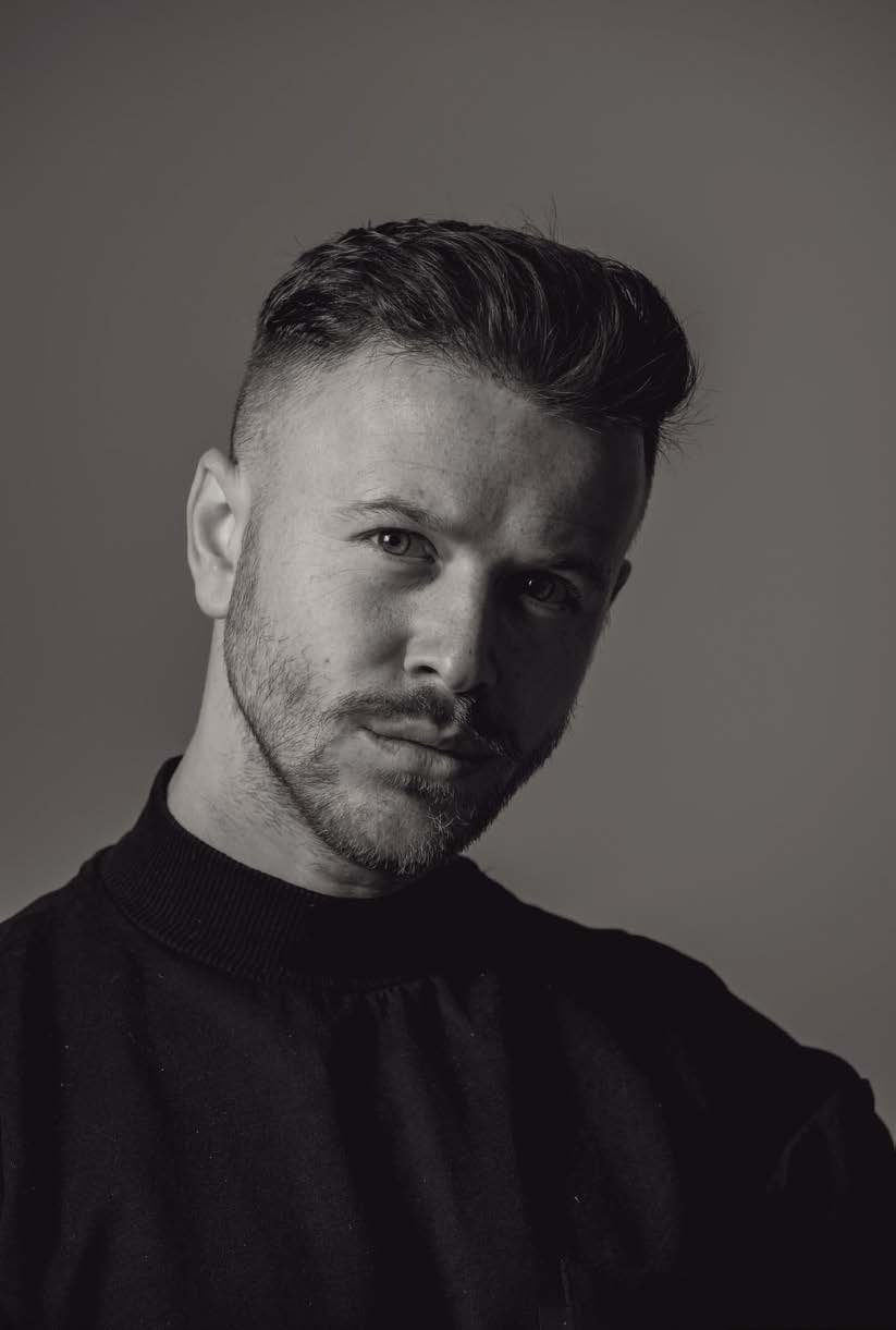 Portrait en noir et blanc accompagnant l’entretien avec Josh Lamonaca : un homme aux côtés rasés, cheveux coiffés vers l’arrière et barbe courte, en pull sombre à col montant, la tête légèrement inclinée.