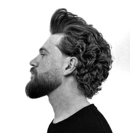 Une coiffure longue et ondulée accompagnée d’une barbe fournie